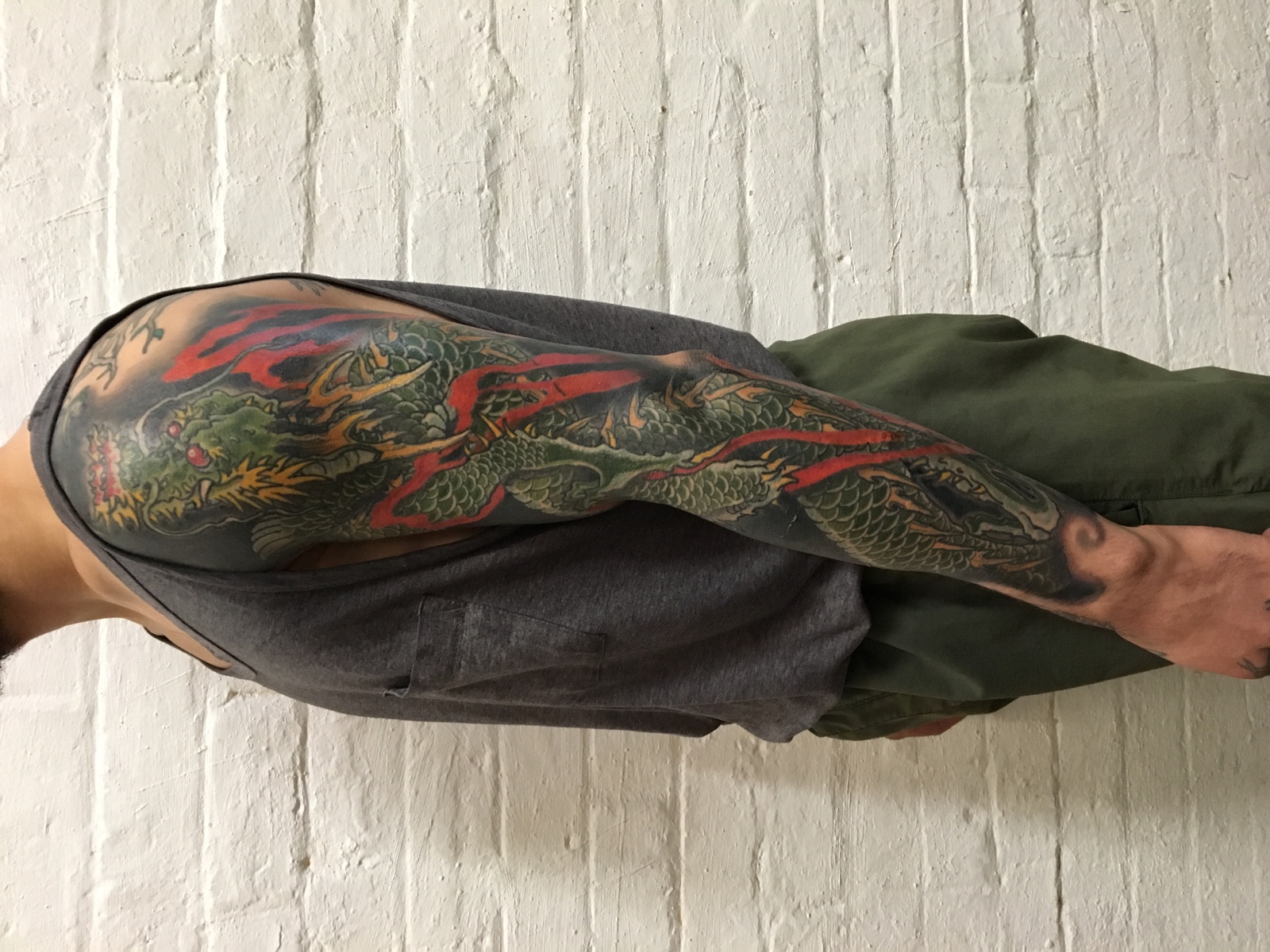 Green Japanese dragon sleeve tattoo with red flames by Tim Dywelska